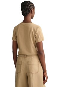 Khaki t-shirt med korta ärmar i mjuk bomull, med en enkel rund halsringning och en avslappnad passform, bärs tillsammans med matchande högmidjade byxor.