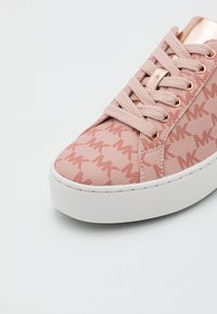 Baskets roses avec semelle blanche, œillets et détails en or rose, tige en tissu avec un motif répétitif de logos "MK", lacées.