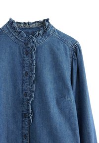 Camicia di denim con colletto a volant, chiusura a bottoni, maniche lunghe e una superficie leggermente texture in una tonalità di blu medio.