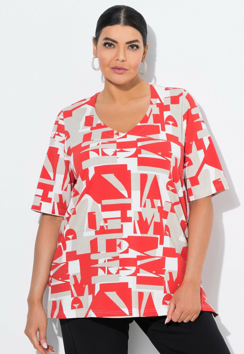 Červené a béžové grafické tričko s výstřihem do V a krátkými rukávy, zdobené abstraktními tvary a textovými vzory, vyrobené z lehkého materiálu.