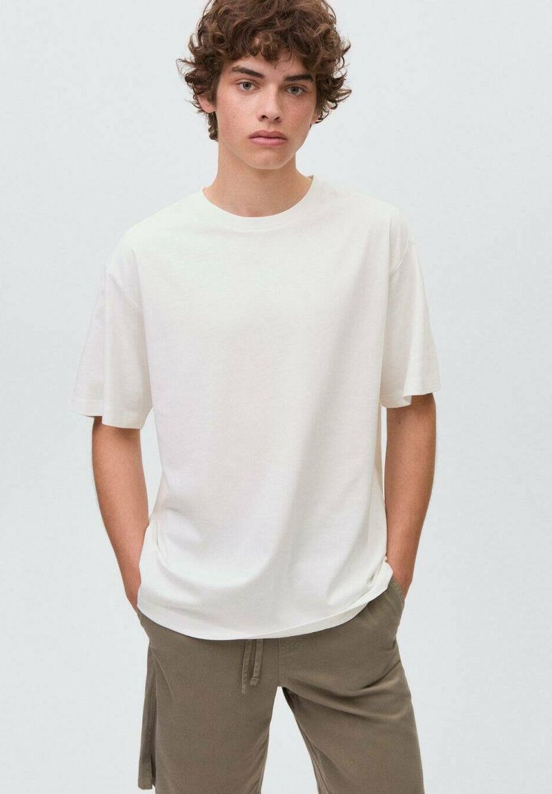 Bílý bavlněný tričko s kulatým výstřihem, krátkými rukávy a volným střihem, kombinované s olivovými kalhotami na šňůrku.