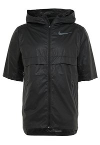 Veste coupe-vent Nike noire à manches courtes avec capuche, fermeture éclair frontale, poches zippées et motif subtil "Just Do It".