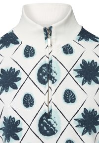 Half-zip pullover met een ribbelige witte kraag. Heeft een patroon van donkerblauwe bladeren en cirkelvormige vormen op een witte achtergrond.