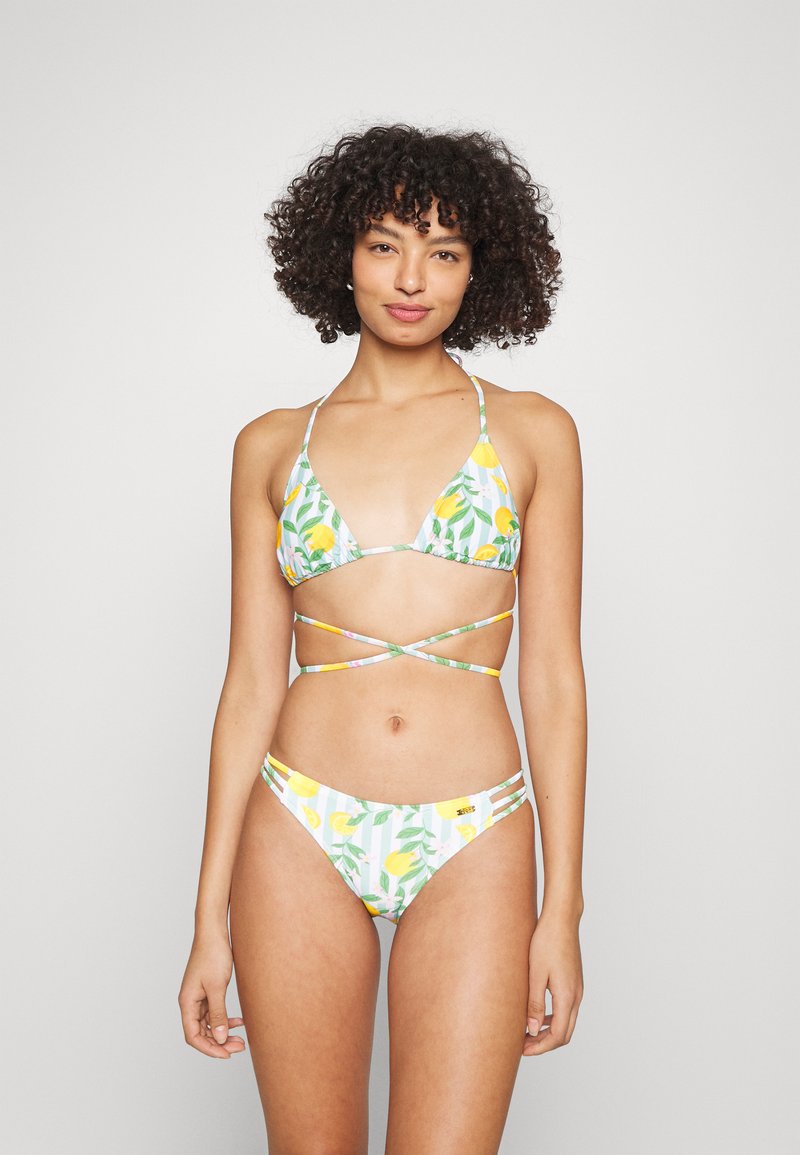 Conjunto de bikini com um top triangular e parte de baixo de cintura baixa em branco, com padrões de limões amarelos e folhas verdes, alças ajustáveis e detalhes listrados.