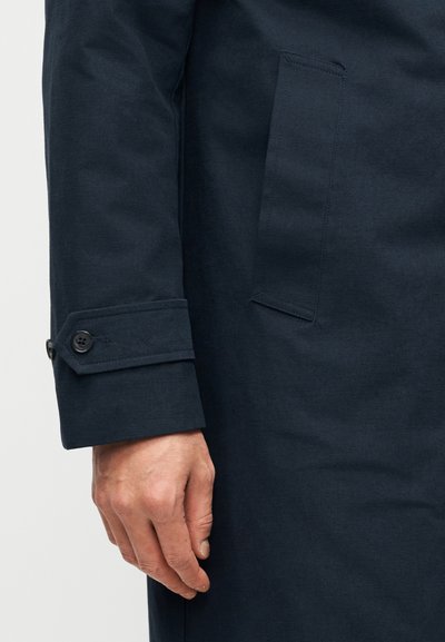 Ναυτικό παλτό με λεπτομέρεια μανσέτας με κουμπί, κομψή υφή υφάσματος και μίνιμαλ σχεδίαση με πλαϊνή τσέπη.