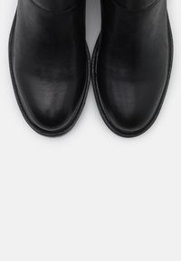 Black leather ankle boots with a smooth finish, rounded toe, and minimal seams. Thick sole with a subtle, durable stitch detail.