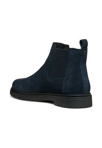 Botas de tobillo de ante azul marino con paneles laterales de malla texturizada y una tira de agarre. Suela de goma plana, forma estilizada y diseño minimalista.