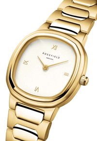 Reloj dorado con caja cuadrada, esfera blanca, números romanos y una correa de metal cepillado con acentos pulidos y una corona.