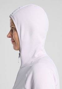 Sweatshirt à capuche violet clair avec une texture lisse, doté d'un zip à l'avant et d'une capuche ajustée qui encadre le visage.