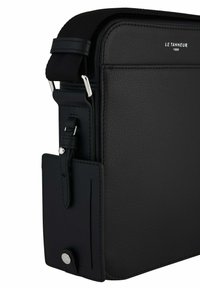 Borsa a tracolla in pelle nera con superficie testurizzata, forma rettangolare, tracolla regolabile e accessori in argento. Presenta una tasca laterale.