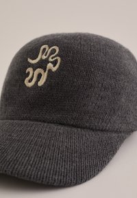 Temno siva pletena kapa z okroglo krono, ki ima kremasto vezeno logo. Rob je ukrivljen, tekstura pa je mehka in gladka.