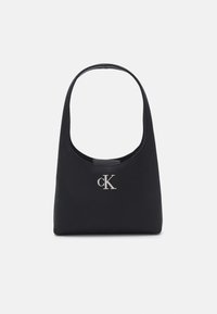 Borsa nera realizzata in materiale texturizzato con tracolla arrotondata e logo 'cK' in argento davanti. Design semplice e minimalista.