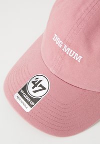 Cap rose en coton, avec le texte brodé "DOG MUM" en blanc, et une étiquette circulaire portant la mention "47 CLEAN UP ADJUSTABLE" en noir et blanc.
