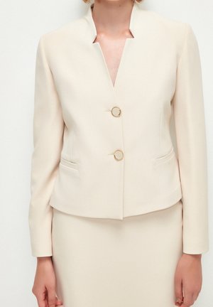 Beige taillierter Blazer mit kragenlosem Design, zwei goldfarbenen runden Knöpfen und seitlichen Taschen. Glattes, leichtes Material.