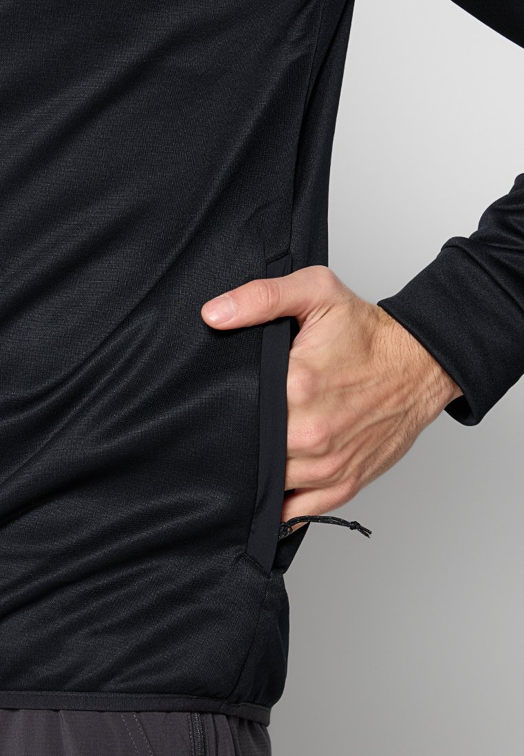 Czarna bluzka z długim rękawem, wykonana z teksturowanej tkaniny, z boczną kieszenią i sznurkiem u dołu dla regulowanego dopasowania.