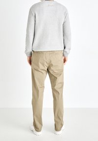Gray ribbed sweater with long sleeves, beige chinos, and white sneakers, viewed from the back against a plain white background.