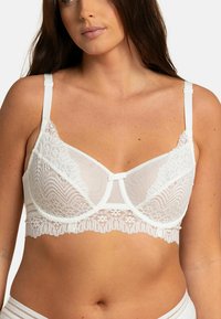 Soutien-gorge blanc avec des détails en dentelle, bonnets en mesh doux et bretelles réglables. Il présente un nœud central et un ourlet en dentelle festonnée.