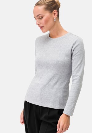 Helles graues Langarm-T-Shirt aus weichem Stoff, mit Rundhalsausschnitt und taillierter Silhouette, kombiniert mit schwarzen Hosen.