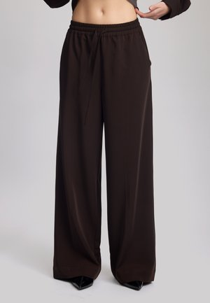 Brown wide-leg pants with an elastic waistband and drawstring detail. Made from smooth fabric, featuring side pockets and a relaxed fit.