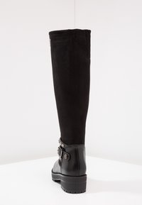 Stivale nero fino al ginocchio con tomaia in suede, punta arrotondata e tacco in pelle lucida. Presenta una cinturino decorativo con dettaglio a fibbia.