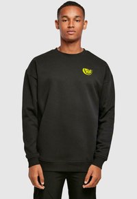 Schwarzes Sweatshirt mit Rundhalsausschnitt, versehen mit einem gelben Zitronenscheiben-Logo auf der linken Brust. Hergestellt aus einem weichen Stoff mit lockerer Passform.
