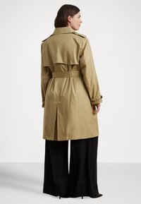 Khaki színű ballonkabát övvel a derékon, vállpántokkal és hátsó sliccel. Hosszú ujjú, fekete, bőszárú nadrág fölött viselik.