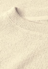 Světle béžový pletený svetr s texturovaným povrchem, s žebrovaným výstřihem a hladkým švem podél límce.