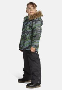 Roheline ja hall kamuflaažjakke koos karvase kapuutsiga, kombineeritud mustade pükste ja mustade kingadega. Omab elastseid varrukaid ja külgmisi lukke.