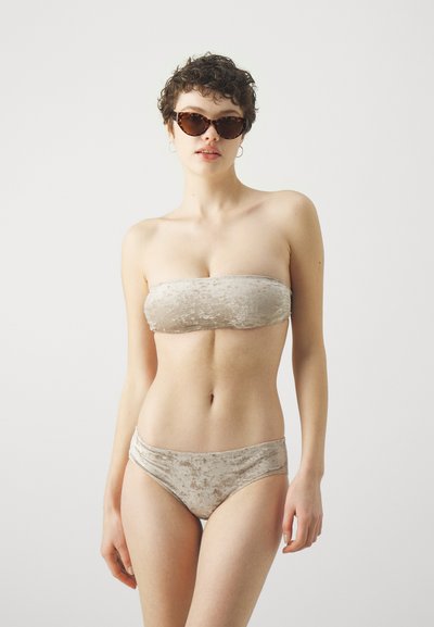 Beidzamais velveta bandeau bikini tops bežā ar atbilstošu augsto jostasvietu apakšējo daļu, kura izceļas ar mīkstu tekstūru un gludu apdari. Aklās šuves ir minimālas.