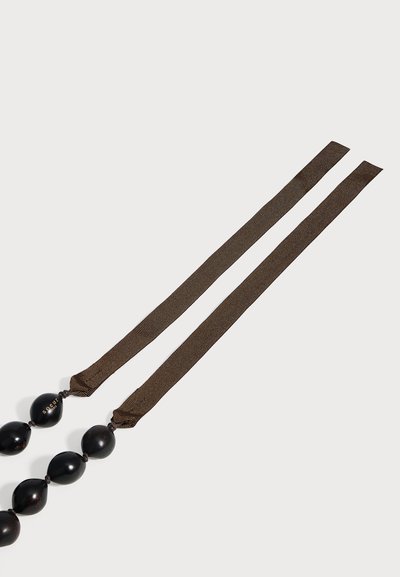 Collier en tissu brun foncé avec de grosses perles rondes noires espacées uniformément sur toute la longueur, posé à plat sur un fond clair.