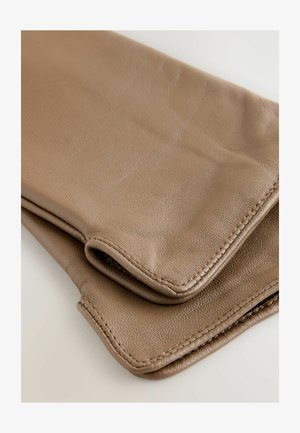 Miękkie brązowe złożone skórzane rękawiczki z widocznym szwem na jasnym tle, ukazujące teksturę i szczegółowe szwy.