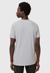 Šedé bavlněné tričko s kulatým výstřihem, krátkými rukávy a volným střihem. Hladká textura a jednoduchý design bez vzorů či akcentů.