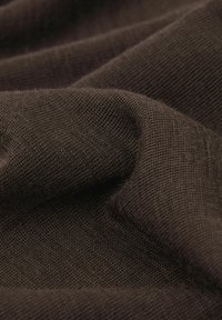 Braun gewebter Stoff mit einer weichen Textur, der ein leicht erhabenes, offenes Strickmuster aufweist. Das Material wirkt leicht und fällt gut.