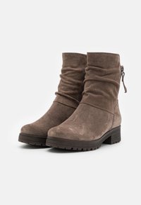 Brune suède ankelstøvler med en slouchy overdel, rund tå og en lynlåsdetalj på siden. Tykk gummisåle for bedre grep.