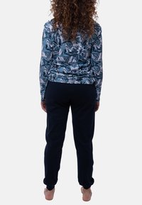 Haut à manches longues à motif floral en bleu et blanc, associé à un pantalon bleu marine. Tissu doux et décontracté avec une coupe ample.
