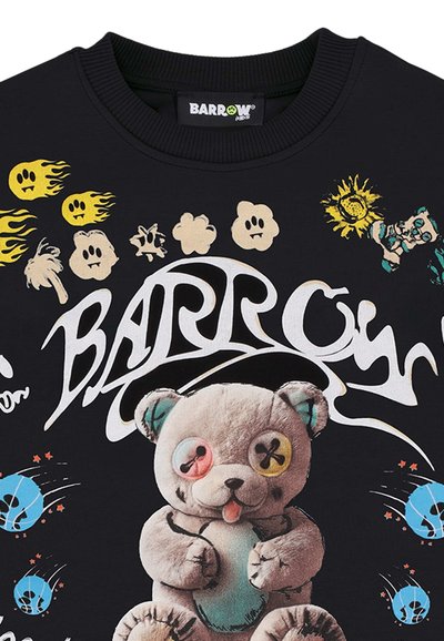 Chemise noire avec un ours en peluche cousu, des yeux en boutons colorés, des emojis jaunes flamboyants, un tournesol et le mot « BARROW » en grand texte blanc stylisé.
