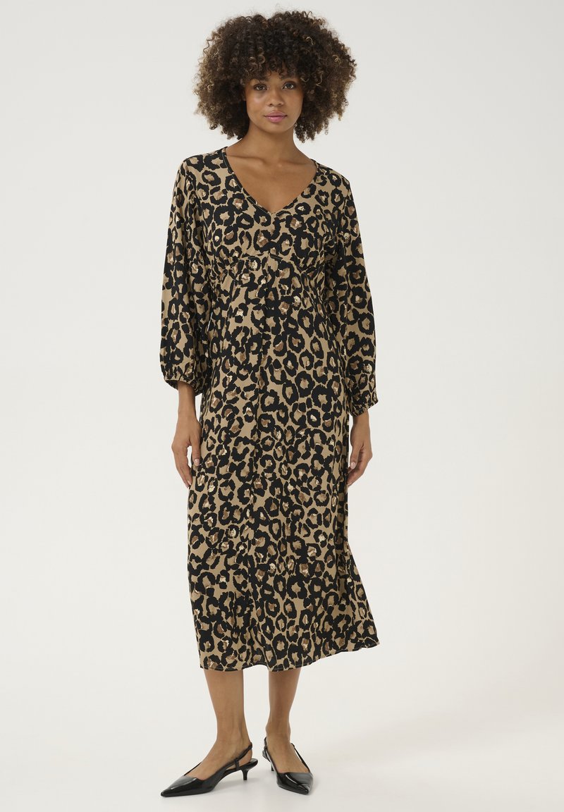 Midi haljina s printom leoparda u bež i crnoj boji, s V-izrezom, nabranim strukom i dugim napuhanim rukavima. Uparena s crnim slingback potpeticama.