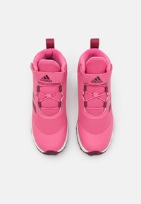 Różowe buty sportowe z textured górą, elastycznymi sznurówkami i wzmocnionym noskiem. Zawierają logo oraz pętle ułatwiające zakładanie.