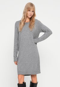 Robe pull en tricot gris avec de longues manches, des poignets et un ourlet côtelés. Présente une coupe décontractée et une texture douce, atteignant le milieu des cuisses.