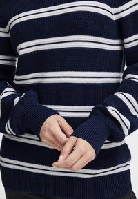 Dunkelblauer Strickpullover mit weißen horizontalen Streifen. Hat einen gerippten Rundhalsausschnitt und Bündchen, mit lockerer Passform und strukturiertem Material.