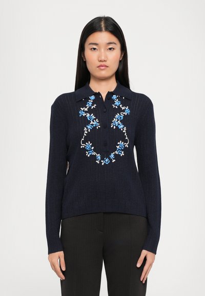 Merine pullover-sviiter, millel on soonikstruktuur ja kraega kaelus, esiküljel valge ja sinise lillekirjaga tikand ning kolm nuppu.