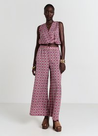 Zweiteiliges Outfit mit einem pinken, gemusterten Crop-Top und weit geschnittenen Hosen mit floralem Design. Der Stoff hat eine glatte Textur.
