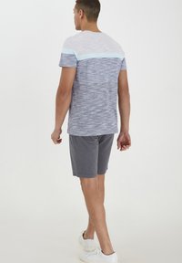Grå og blå stribet t-shirt med korte ærmer, der har en lyseblå vandret accent. Kombineret med grå shorts og hvide sneakers.