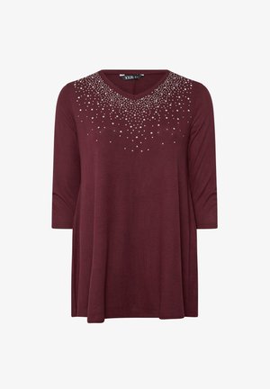 Bordeaux tuniek met driekwart mouwen, V-hals en versierd met zilveren nailheads in een verlooppatroon op de bovenste voorkant.