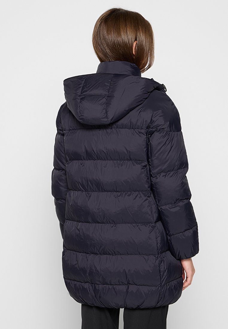 Marineblaue Steppjacke mit Kapuze, die ein gesteppter Look und eine mittellange Schnittführung aufweist. Glattes, glänzendes Material mit elastischen Bündchen.