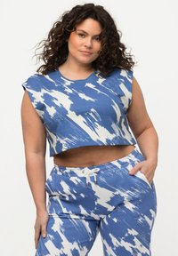 Top corto azul y blanco con un patrón de pinceladas, combinado con pantalones a juego que cuentan con una cinturilla elástica y bolsillos laterales.