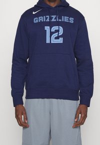 Felpa blu navy con tasca frontale, presenta la scritta "GRIZZLIES" e il numero "12" in azzurro chiaro. Logo Nike in bianco sulla spalla.