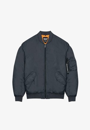 Mørkegrå bomberjakke med en frontlynlås, ribbede manchetter og sidelommer. Har orange foring og en værktøjslomme på den ene ærme.