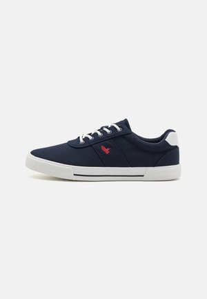 Ναυτικές καμβά sneakers με λευκές σόλες, που διαθέτουν κόκκινο λογότυπο, λευκά οπές και μπλε κορδόνια. Λείος υφής με χαμηλό σχέδιο.