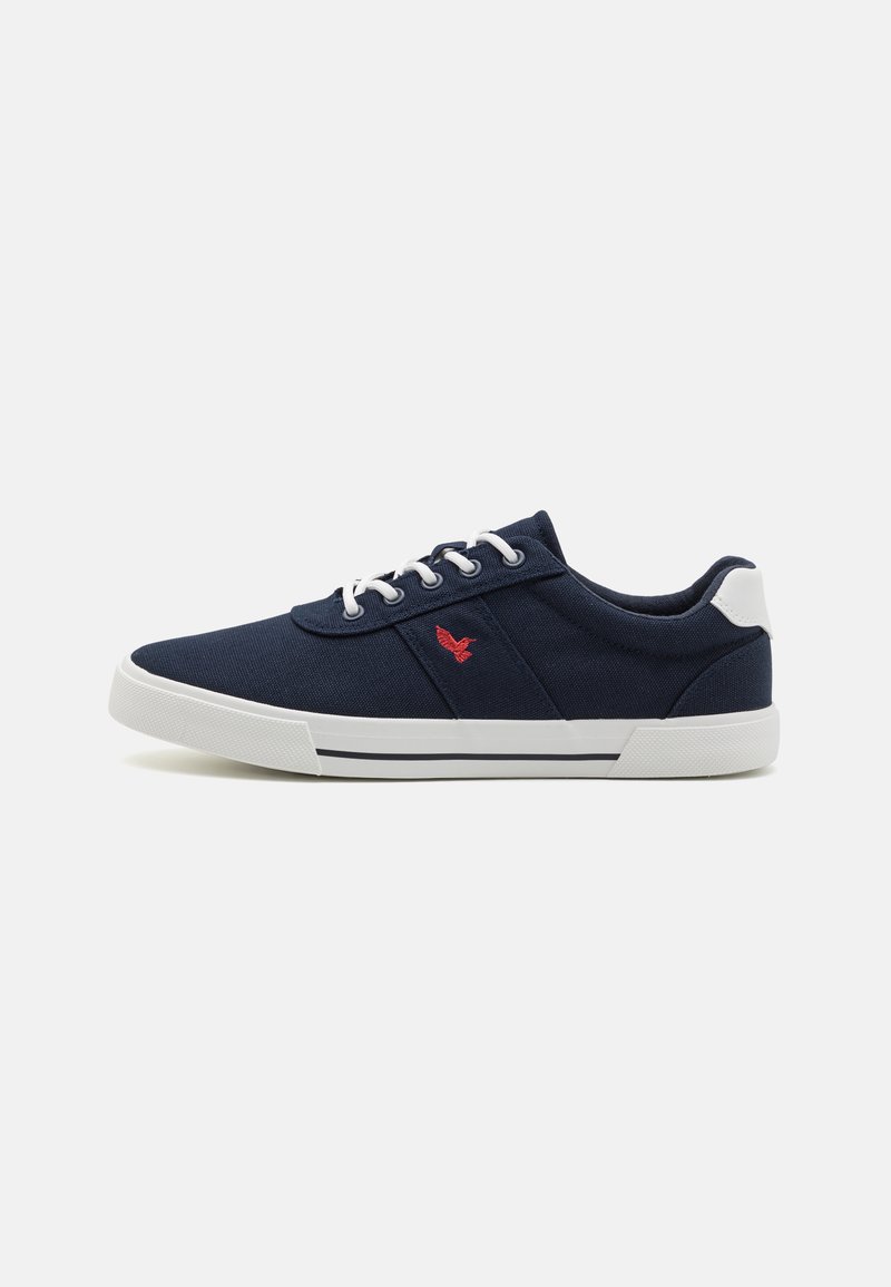 Navy canvas sneakers with white soles, featuring a red logo, white eyelets, and blue laces. Smooth texture with a low-top design.